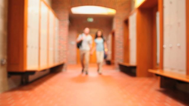 Scene shows a couple walking along a warm-toned corridor, hinting at a campus atmosphere. The blurred focus suggests active movement and could convey themes of everyday student life or educational settings. This might be perfect for projects related to college life, motivational content, or education-related advertising.