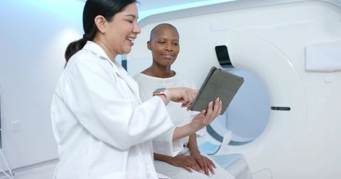 Radiology tech consulting with african american patient before ct scan using tablet