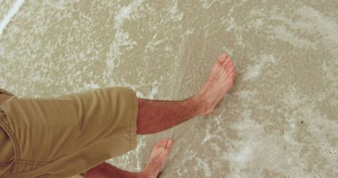 Man Walking Barefoot on Sandy Beach with Gentle Surf