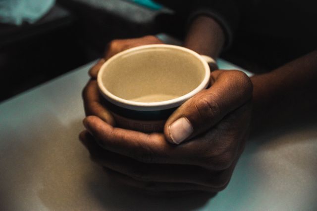 This image shows a close-up view of hands holding a warm coffee mug, making it perfect for use in content related to comfort, relaxation, or winter themes. It can be used in advertisements for coffee brands, blog posts about cozy winter mornings, or any marketing materials highlighting comforting and warm beverages.