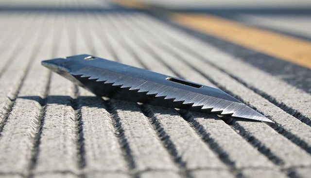Glinting serrated steel blade lying diagonally on grooved concrete pavement and blurred yellow line
