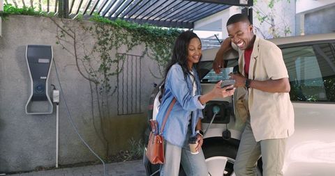 Friends Charging Electric Car While Enjoying Leisure Time