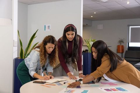 Diverse women collaborating over color swatches in modern office lounge design review