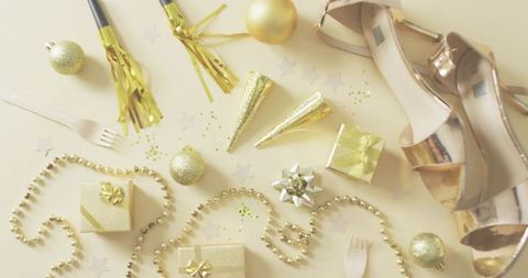 Rose-gold sandals flatlay with gold gifts, beads and party accessories, ample copy space