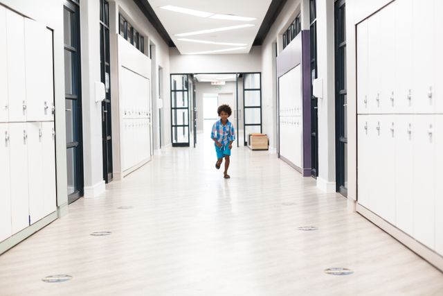 Full length of african american schoolboy running in school corridor at school. unaltered, education, childhood, happiness and school concept.