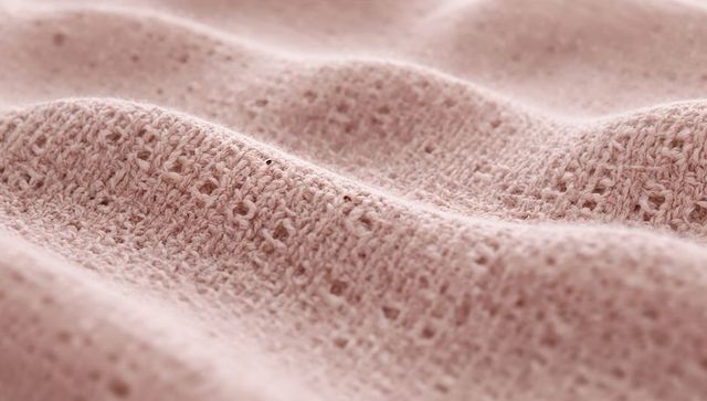 Soft pink knitted fabric macro folds and textured yarn detail for textile backgrounds