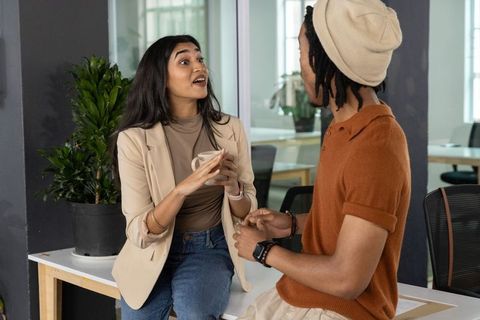 Animated office conversation between coworkers sharing coffee and ideas during break