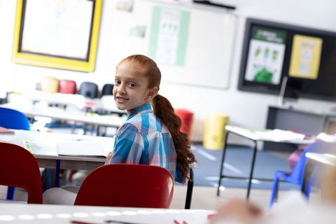 Smiling Schoolgirl Turning Back in Colorful Classroom
