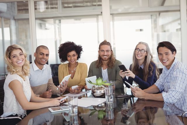 Portrait of smiling young business people sitting together at creative office desk