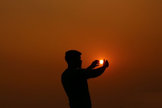 Silhouette of Man Holding Setting Sun at Sunset - Download Free Stock Photos Pikwizard.com