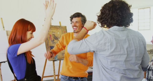 This image shows a group of joyful artists celebrating their success in an art studio. It portrays teamwork, happiness, and creative collaboration. Perfect for creative industry promotions, teamwork concepts, and advertisements focusing on joyful, successful, and collaborative environments.