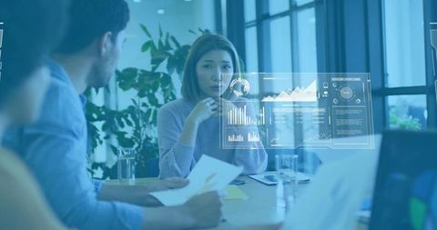 Asian businesswoman presenting data in collaborative office meeting with holographic charts