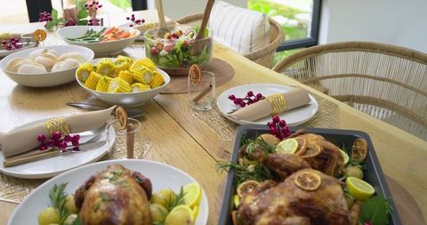 Roasted Whole Chickens Resting on Rustic Wooden Table with Corn, Salad and Garnishes