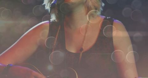 Teen singer performing acoustic guitar onstage with bokeh lights and lens flare