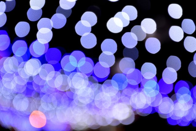 Abstract defocused blue lights creating a bokeh effect against a dark background. Perfect for use in festive, holiday, and celebratory contexts. Great for backgrounds in marketing materials, website banners, and digital designs to add a touch of sparkle and mystery.