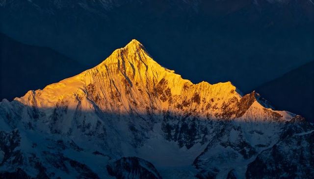 Gold-Lit Summit at Sunrise on Snow-Covered Pyramidal Peak Over Deep Blue Glacier Cirque