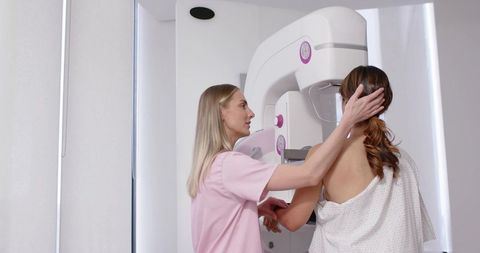 Radiology technologist positioning patient for mammogram during breast screening visit
