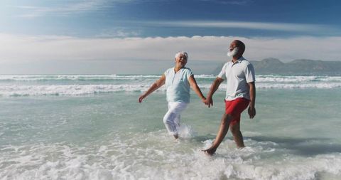 Happy retired couple walking on pristine beach