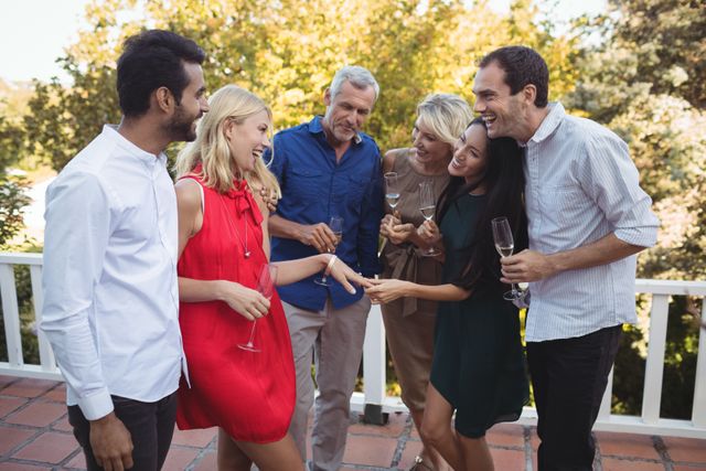 Group of friends celebrating engagement on balcony. Woman showing engagement ring while others admire and smile. Ideal for use in articles about engagements, social gatherings, friendship, and celebrations.