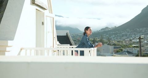Woman Reflecting on Balcony Overlooking Serene Hills