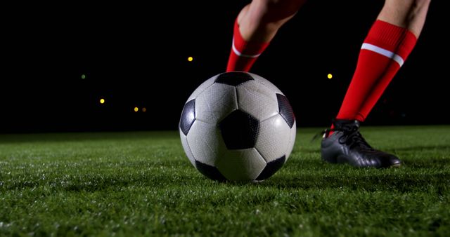 A soccer player prepares to kick a ball on a lit pitch, evoking the game's energy. - Download Free Stock Photos Pikwizard.com