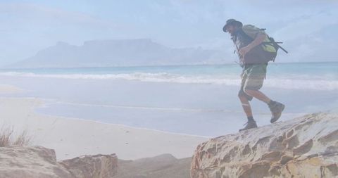 Male hiker exploring coastal cliff on sunny day