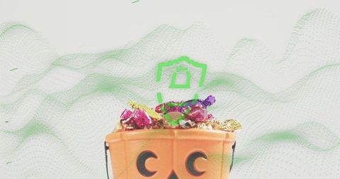 Jack-o-lantern candy bucket overflowing with colorful wrapped sweets and metallic foil