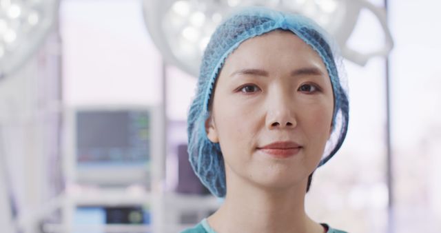 Image portrait of smiling asian female surgeon wearing surgical cap in operating theatre, copy space. Hospital, medical and healthcare services.