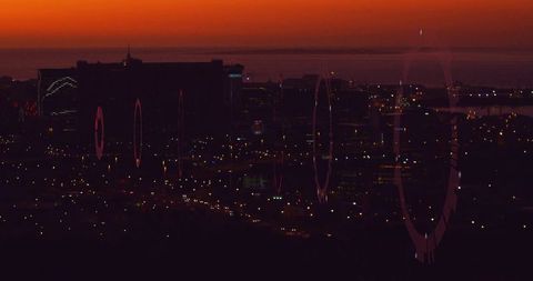 City Skyline at Dusk with Lens Flare Effects Over Hillside Ridge