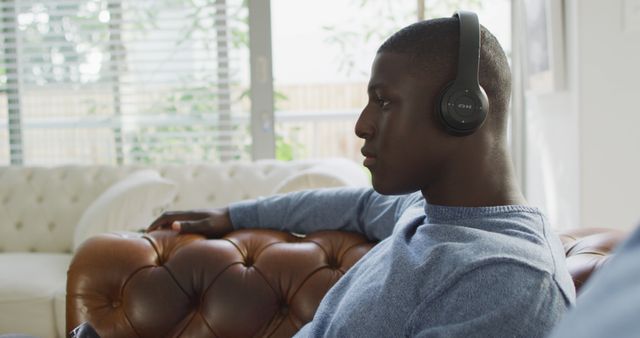 Image of african american man using headphones and listening to music. Domestic life, using technology at home.