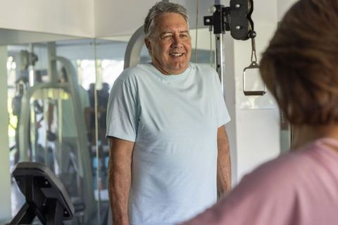 Mature man and senior woman training together on cable machine smiling during workout