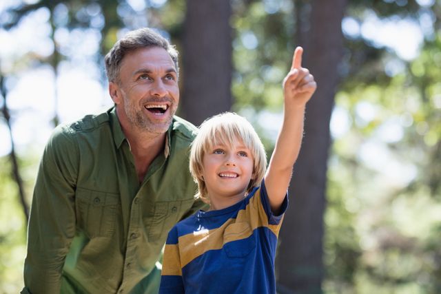 Little boy showing something to cheerful father while hiking in forest