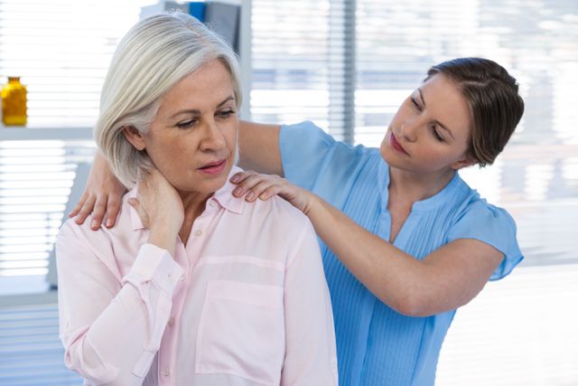 This image shows a doctor massaging an elderly woman's shoulder in a clinic setting. It can be used for articles or advertisements related to healthcare, physical therapy, pain management, senior care, and wellness programs. It highlights the importance of professional medical care and physical therapy in treating shoulder pain and promoting overall health.