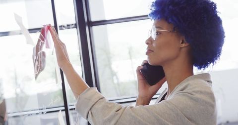 Businesswoman with blue afro discussing project on smartphone