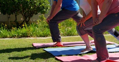Adults practicing forward lunges on yoga mats outdoors