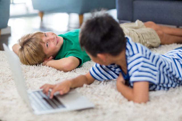 Siblings interacting with each other while using laptop in living room