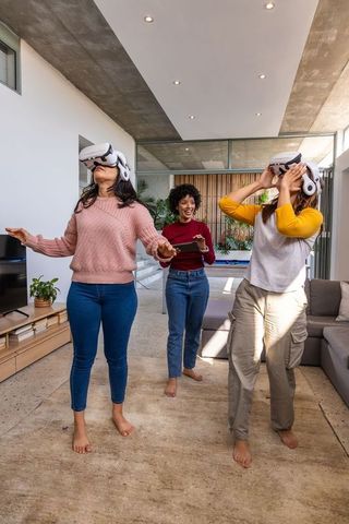Female friends experiencing virtual reality at home, playing vr games together, barefoot