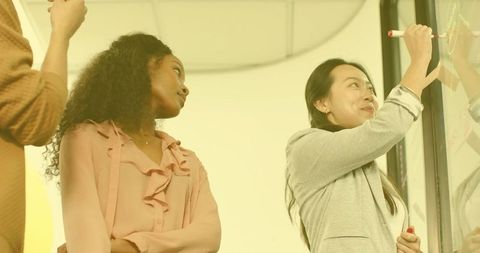 Diverse Team Collaborating on Project Using Glass Board