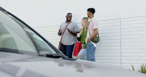 Diverse friends laughing and chatting on urban sidewalk holding coffee and shopping bag