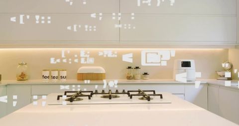 Minimalist white kitchen island built-in gas cooktop, labeled canisters, warm lighting