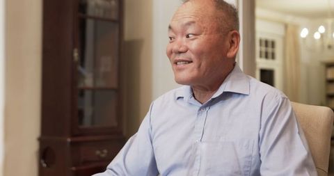 Asian Man Smiling Conversationalist in Comfortable Home Setting