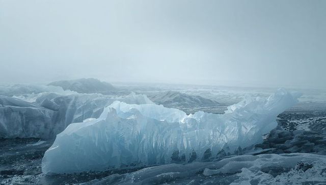 Jagged blue ice formation rising on glacial shoreline with translucent ridges and frost