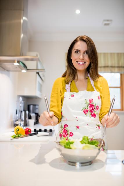 Beautiful woman preparing salad in kitchen at home