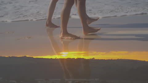 Couple Walking on Beach During Sunset with Wave Reflections