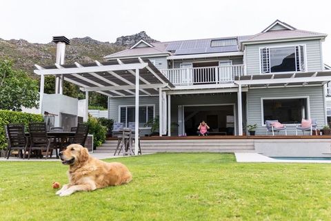 Golden retriever relaxing on lawn in backyard with woman using smartphone on deck