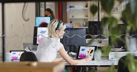 Creative designer drawing on tablet with stylus in modern coworking studio