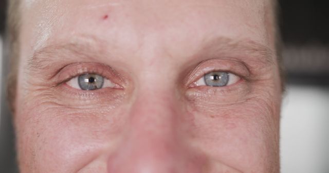This image captures a detailed close-up view of a mature man's eyes, focusing on facial wrinkles and blue iris. It is ideal for use in healthcare and skincare advertisements, aging studies, emotional expression analysis, and any projects related to the human experience or detailed skin texture.