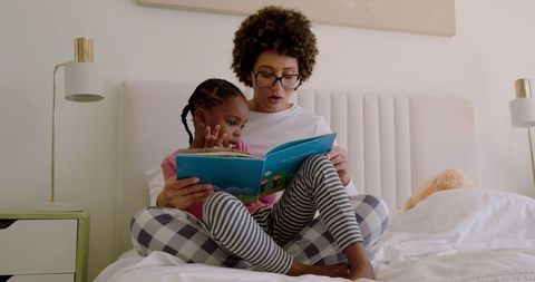 Mother and Child Reading Storybook on Bed