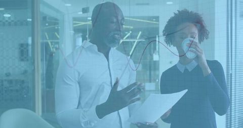 Discussing financial data on glass wall with red line graph in modern office