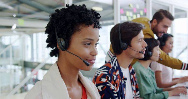 Customer service professionals work in a bright office. Diverse team provides support in a busy call center environment.